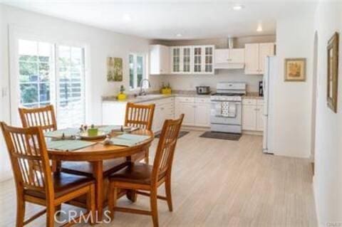 kitchen featuring range with gas stovetop, a sink, light wood-style flooring, light countertops, and white cabinetry
