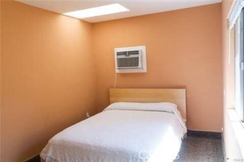 bedroom featuring a wall mounted air conditioner and baseboards