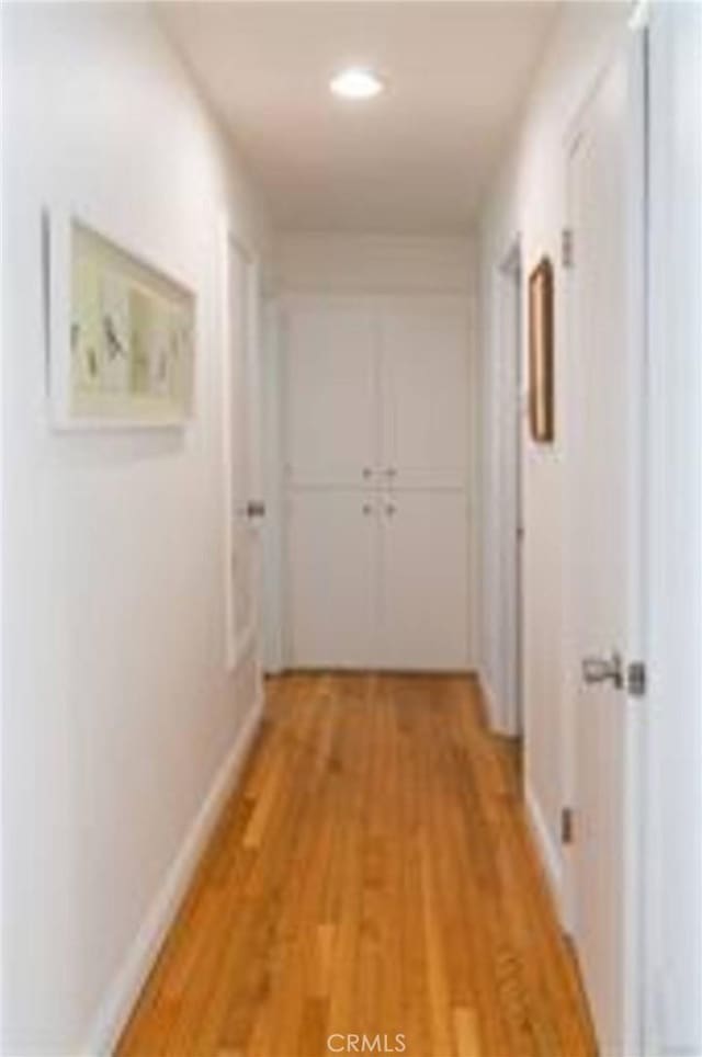 hall with light wood-style flooring and baseboards
