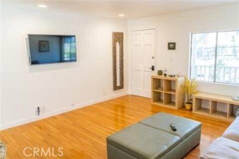 living area with baseboards, wood finished floors, and recessed lighting