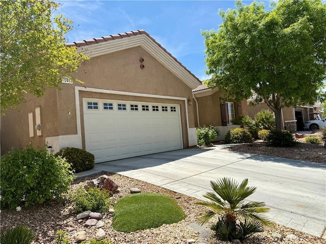 10485 Nobleton Rd, Apple Valley, CA 92308 - view of front of property featuring a garage, driveway, a tiled roof, and stucco siding