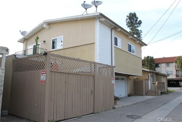 exterior space with stucco siding, fence, and a garage