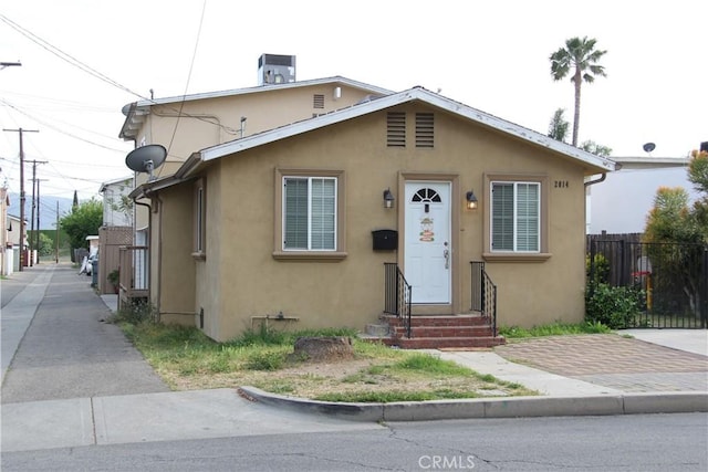 bungalow-style house featuring fence, entry steps, and stucco siding