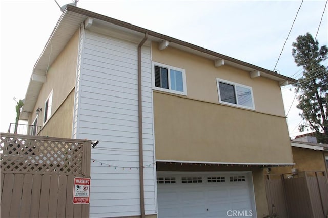 view of home's exterior with fence, a garage, and stucco siding