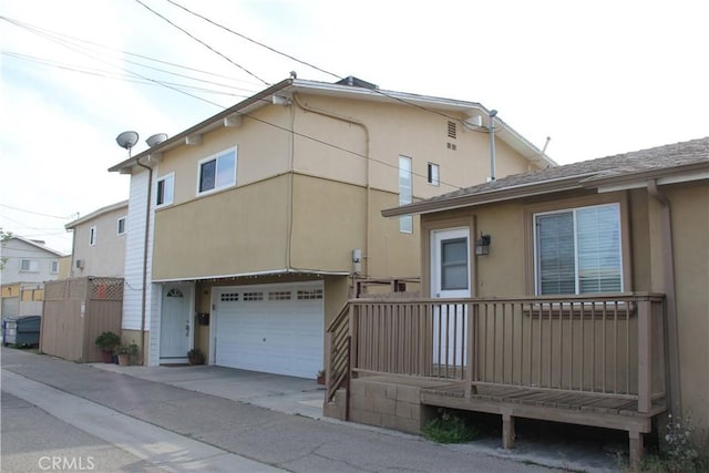 back of house with an attached garage, concrete driveway, and stucco siding
