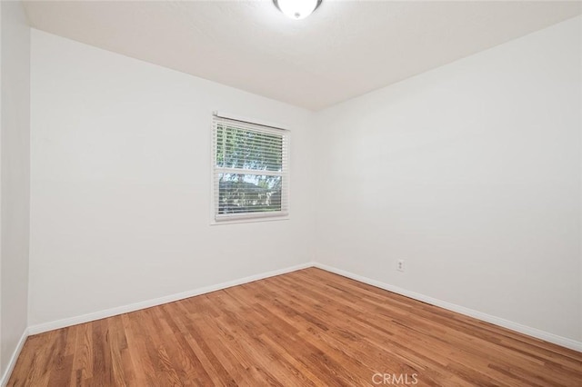 empty room with baseboards and wood finished floors