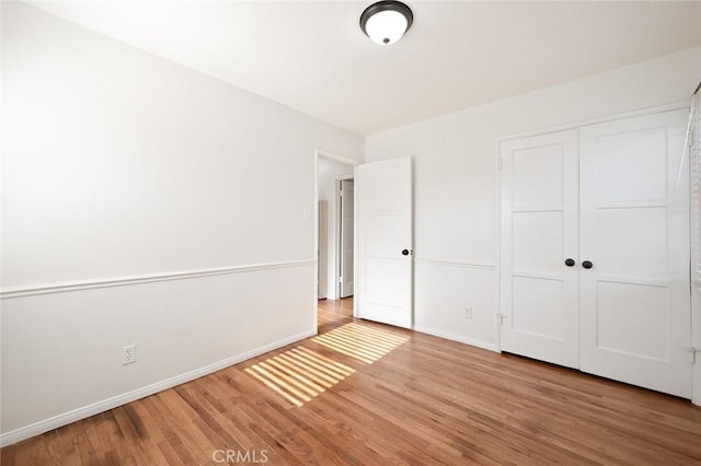 unfurnished bedroom featuring a closet, baseboards, and light wood-type flooring