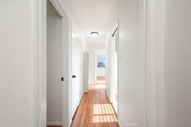corridor featuring light wood-type flooring and baseboards