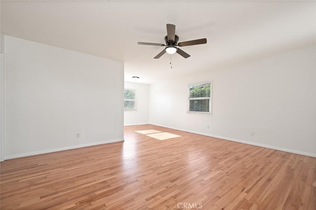 spare room featuring a ceiling fan, light wood-type flooring, and a wealth of natural light