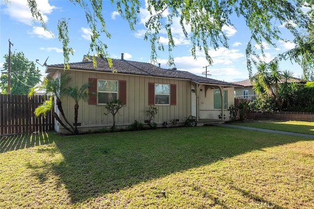 view of front of property featuring board and batten siding, fence, and a front yard