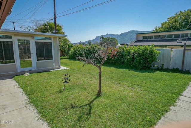 view of yard featuring a mountain view, fence, and a sunroom