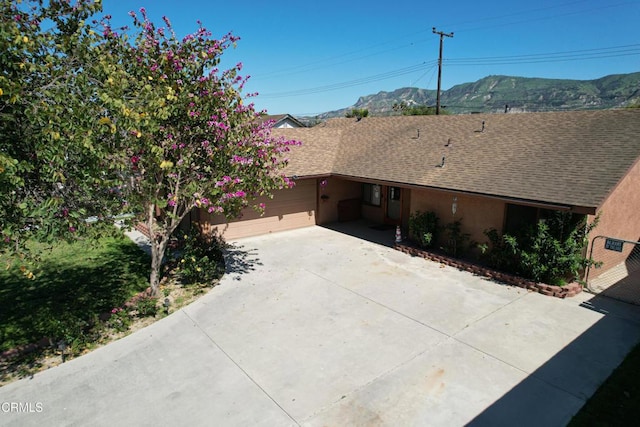 view of front of property with a mountain view, an attached garage, concrete driveway, and roof with shingles