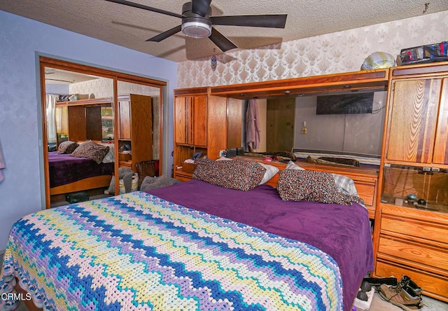 bedroom featuring a closet, a textured ceiling, a ceiling fan, and wallpapered walls