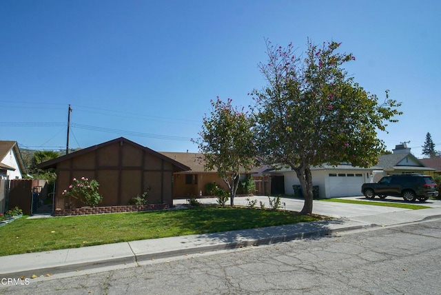 ranch-style house with driveway, fence, a front yard, and an attached garage