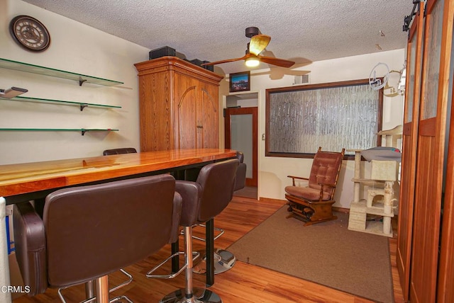 bar with visible vents, wood finished floors, ceiling fan, and a textured ceiling