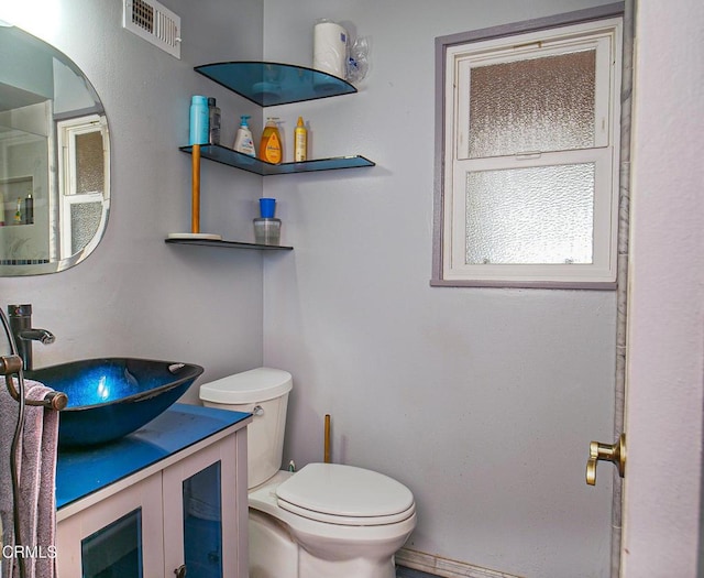 bathroom with toilet, visible vents, and vanity