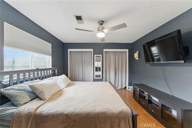 bedroom with ceiling fan, visible vents, and multiple windows