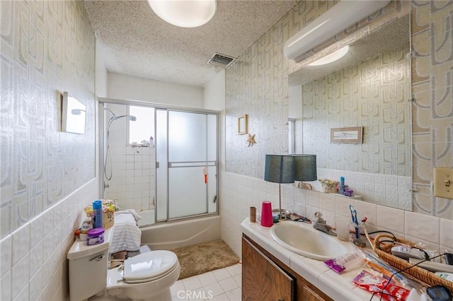 full bath with toilet, visible vents, tile patterned flooring, combined bath / shower with glass door, and vanity
