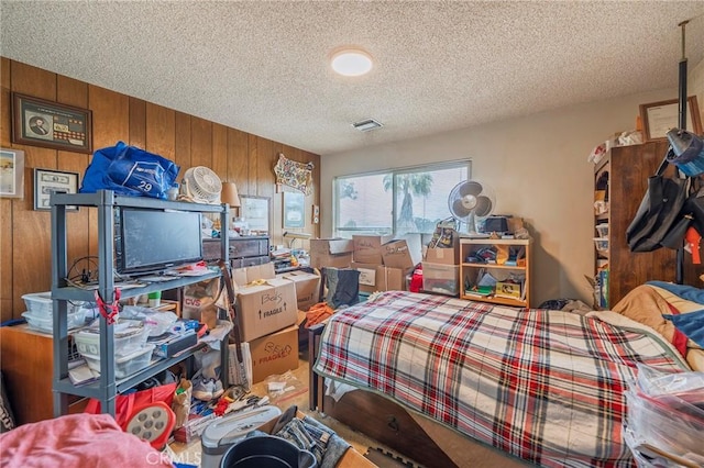 carpeted bedroom with visible vents, wood walls, and a textured ceiling