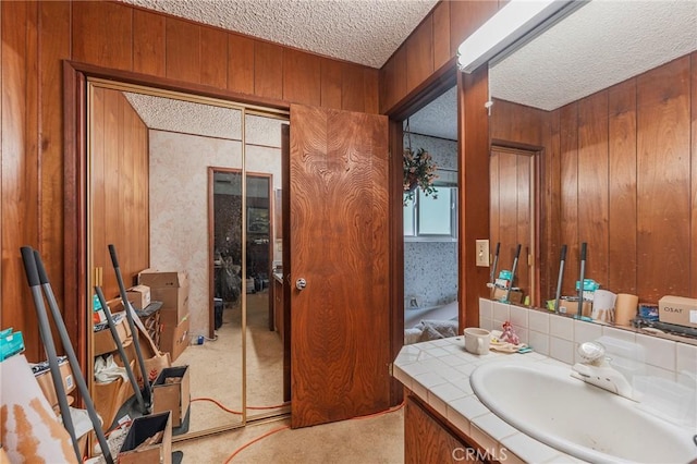 bathroom featuring wooden walls, vanity, and a textured ceiling
