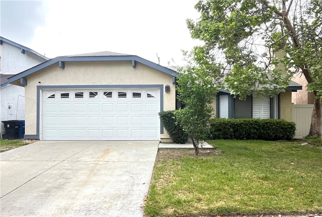 single story home featuring stucco siding, an attached garage, concrete driveway, and a front yard