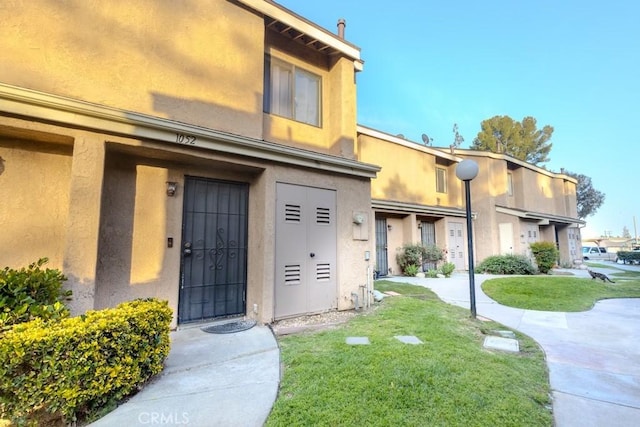 exterior space with stucco siding and a front yard