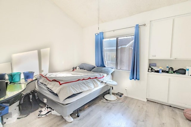 bedroom featuring baseboards, vaulted ceiling, and light wood finished floors