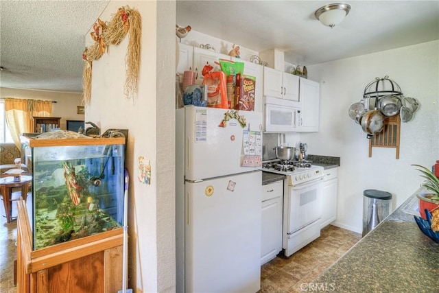 kitchen featuring white cabinets, dark countertops, white appliances, and a textured ceiling