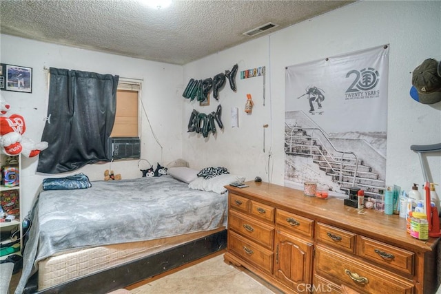 bedroom with cooling unit, a textured ceiling, and visible vents