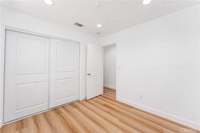 unfurnished bedroom with a closet, baseboards, recessed lighting, and light wood-style floors
