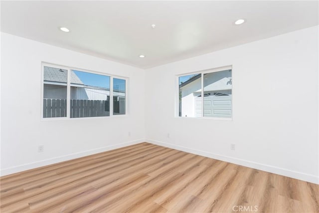 empty room with light wood finished floors, baseboards, and recessed lighting