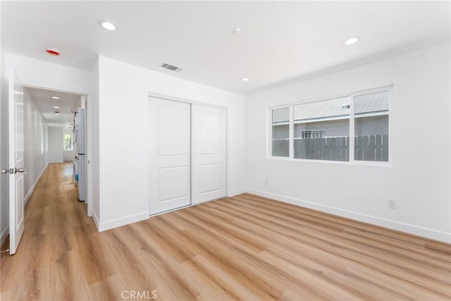 unfurnished bedroom featuring light wood-type flooring, baseboards, recessed lighting, and a closet