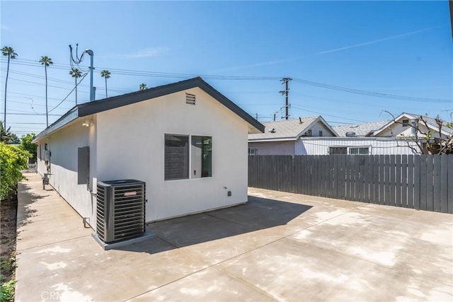 back of house featuring central AC unit, fence, a patio, and stucco siding