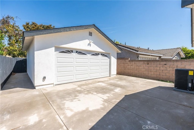 garage with central AC unit, fence, and driveway