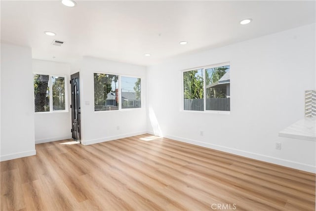 spare room with healthy amount of natural light, recessed lighting, light wood finished floors, and baseboards