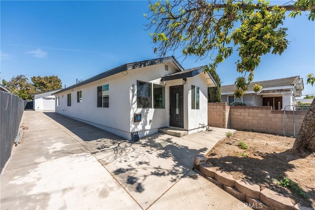 view of front of house featuring fence, a patio, and an outbuilding