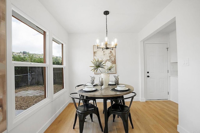 dining room with an inviting chandelier, light wood-style floors, and baseboards
