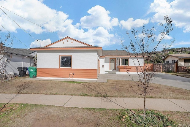view of front of house with fence, concrete driveway, and stucco siding