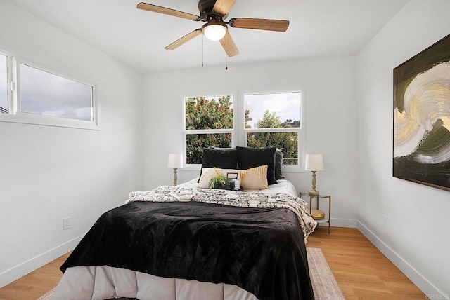 bedroom with light wood finished floors, baseboards, and ceiling fan