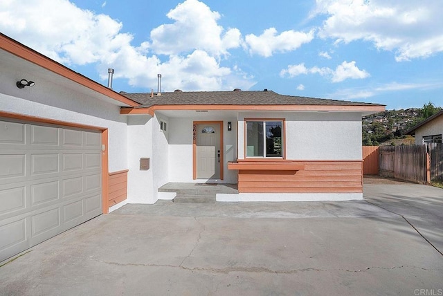 view of front facade with stucco siding, fence, and a garage