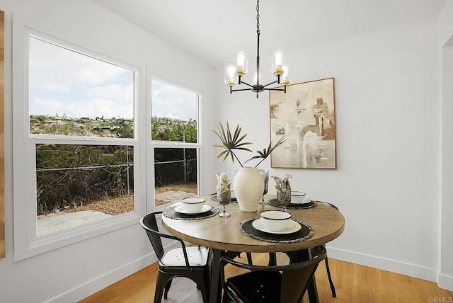 dining space featuring light wood-type flooring, baseboards, and a notable chandelier