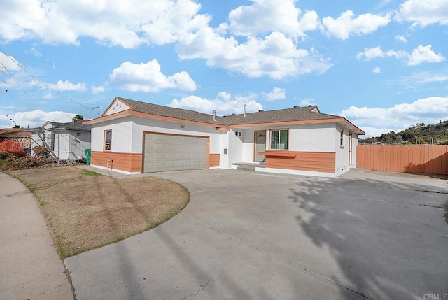single story home featuring stucco siding, an attached garage, fence, and driveway