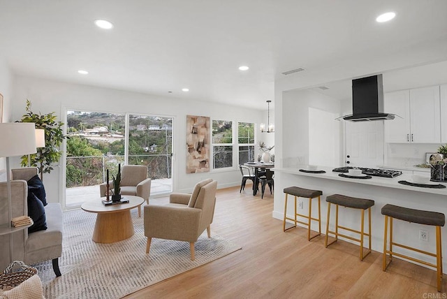 living area featuring recessed lighting, visible vents, light wood-style floors, baseboards, and a chandelier