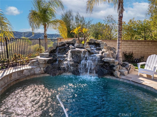 view of pool featuring a garden pond, a fenced in pool, a fenced backyard, and a mountain view