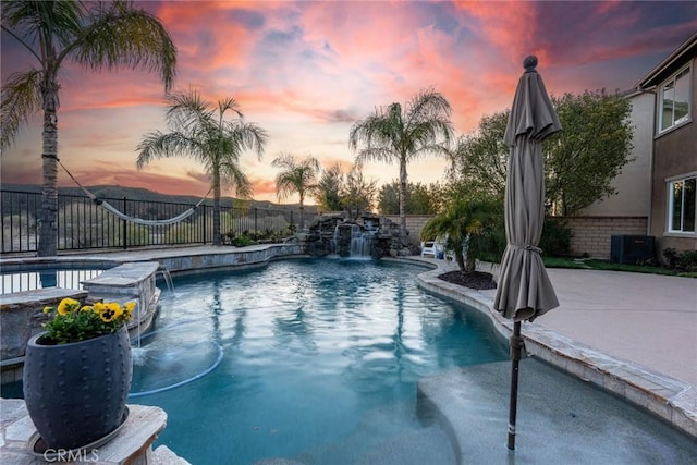 view of swimming pool featuring a fenced backyard, central air condition unit, a patio, and a pool with connected hot tub
