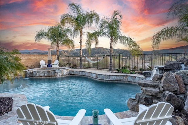view of swimming pool featuring a fenced backyard and a pool with connected hot tub