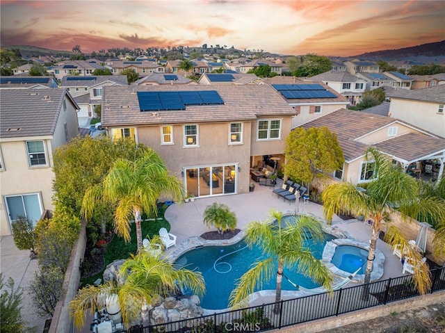 22514 Brightwood Pl, Saugus, CA 91350 - back of house at dusk featuring stucco siding, a residential view, a fenced backyard, and roof mounted solar panels