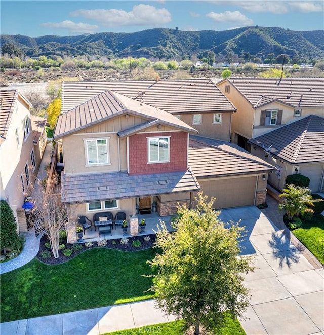 craftsman-style house with a mountain view, stone siding, concrete driveway, a garage, and an outdoor hangout area