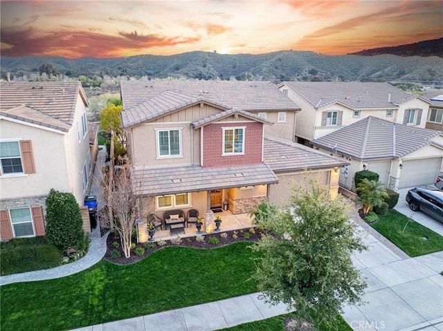 view of front of house with concrete driveway, outdoor lounge area, a mountain view, a yard, and stucco siding