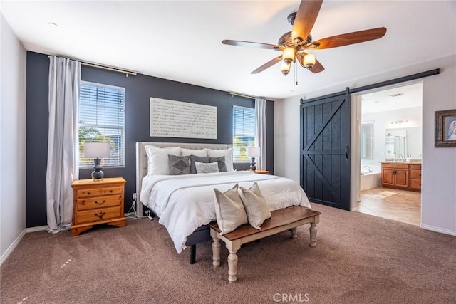 bedroom featuring a barn door, baseboards, light colored carpet, and ensuite bathroom